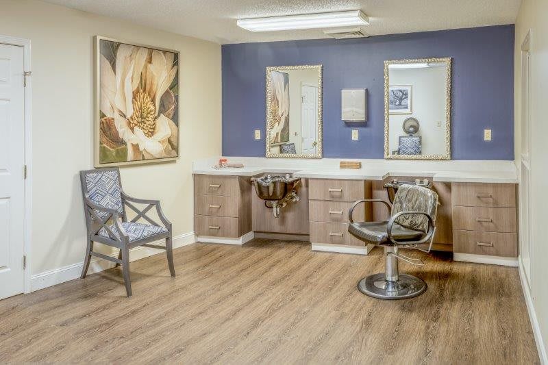 A stylish and well-organized salon space with a hair styling chair, mirrors, and artwork on the walls.