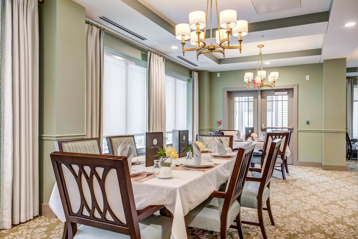 A sophisticated dining room with a large table, elegant chairs, and stylish chandeliers.
