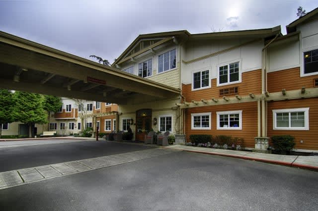 A modern building entrance with an overhanging structure and driveway.