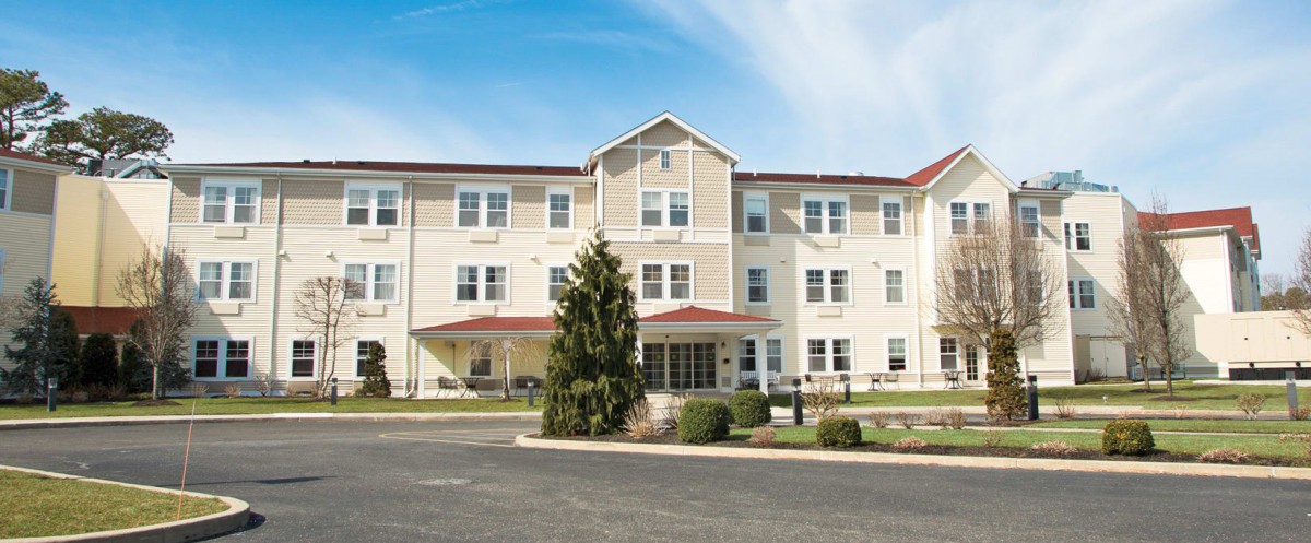 A large residential building with multiple floors, featuring a central entrance and neatly maintained surroundings.