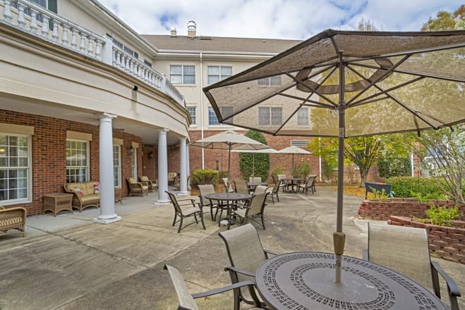 An outdoor patio area with tables, chairs, and umbrellas in front of a building.