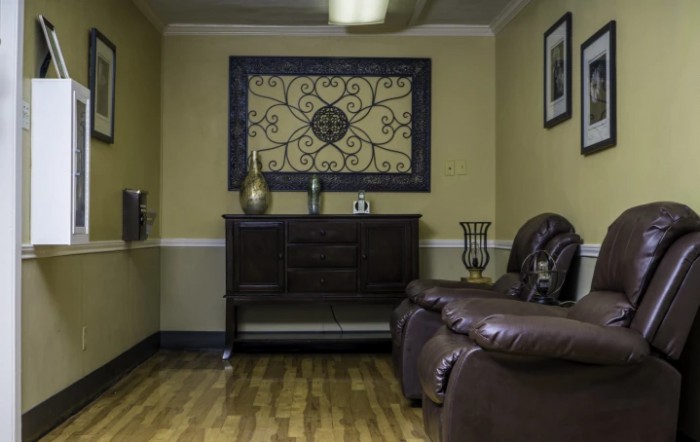 A cozy living room with a leather sofa, decorative wall art, and a wooden cabinet on a hardwood floor.