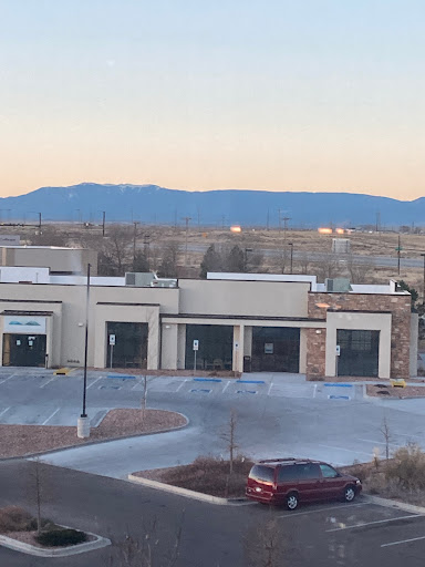 A view of a shopping center with empty storefronts and mountains in the background during sunset.