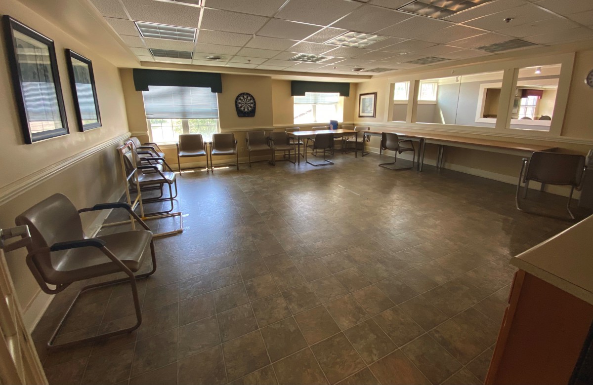 An empty meeting room with chairs along the walls and large windows.