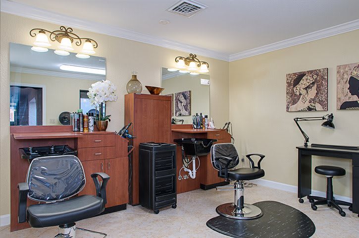 A cozy hair salon interior featuring styling chairs and mirrors, with hairdressing tools neatly arranged on wooden counters.