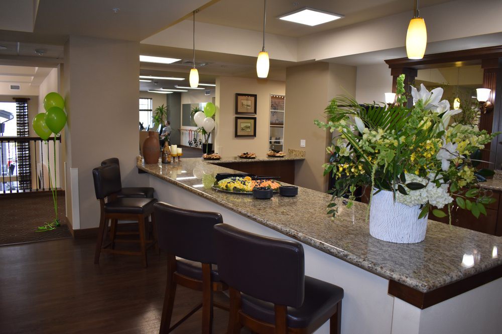 A modern office reception area with a granite counter, seating, and decorative plants.