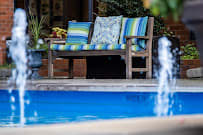 A cozy outdoor bench with colorful cushions by a bright blue swimming pool.