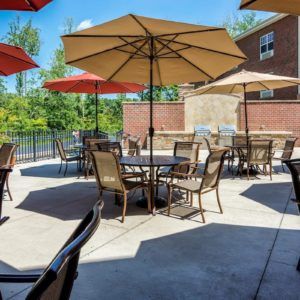 A sunny outdoor patio with tables, chairs, and umbrellas.