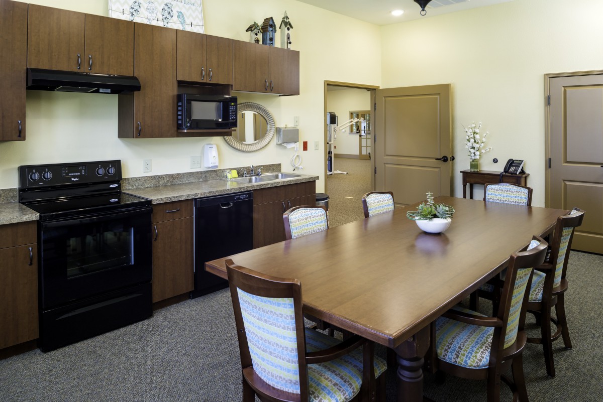 A modern kitchen and dining area featuring a wooden table with chairs, equipped with appliances like a microwave and stove.