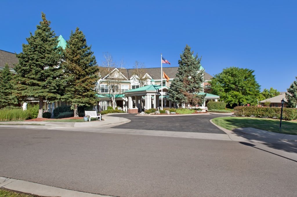 A large building with a grand entrance, surrounded by trees and set against a clear blue sky.