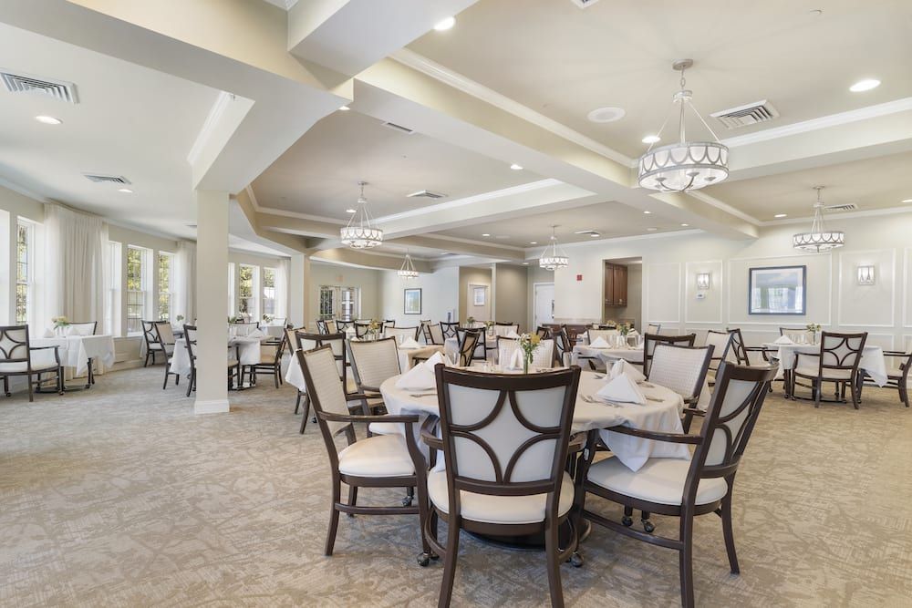 An elegant dining room with neatly arranged tables and chairs, featuring a sophisticated chandelier.