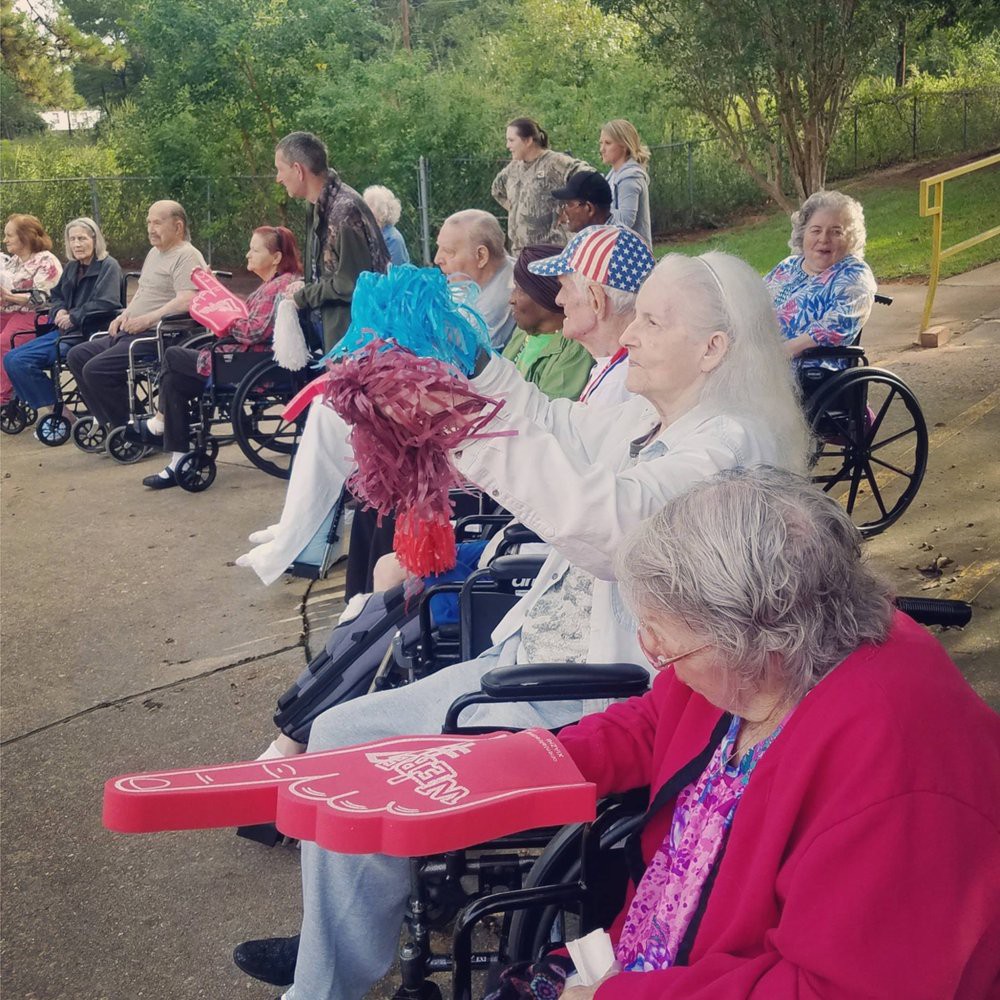 A group of elderly individuals enjoying an outdoor gathering while seated in wheelchairs.