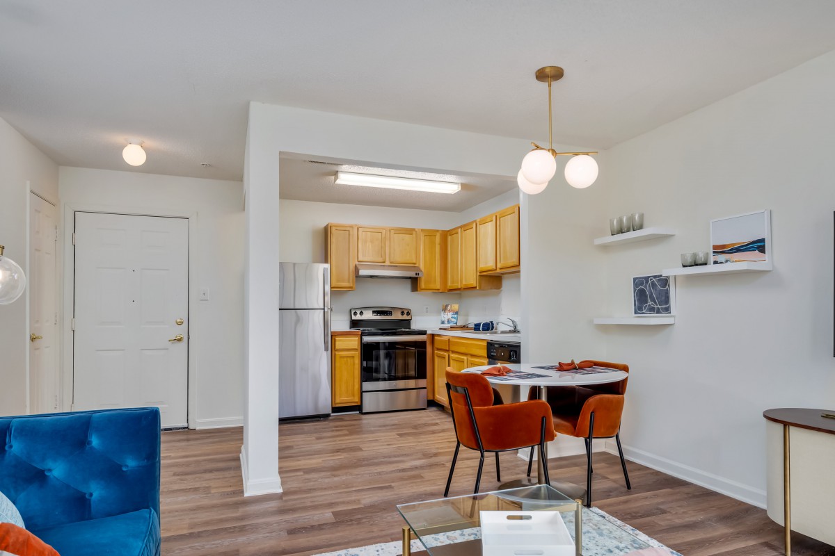 A modern open floor plan kitchen and dining area with wooden cabinets and stainless steel appliances.
