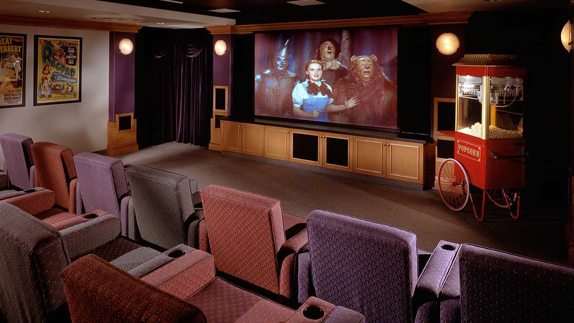 A luxurious home theater with comfortable seating and a large screen displaying a movie.