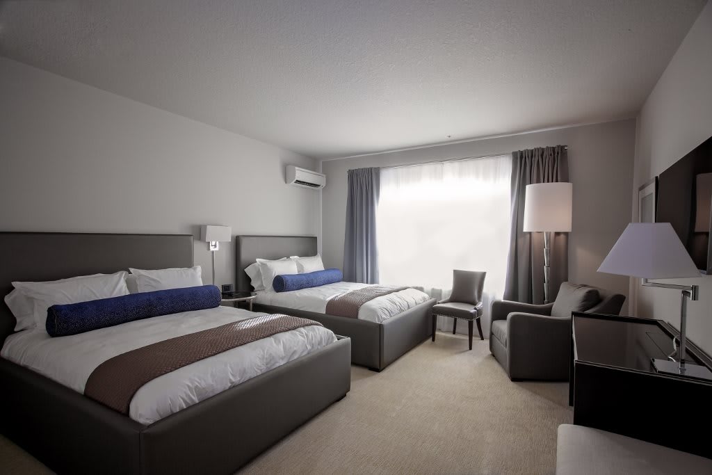 A modern hotel room featuring two comfortable beds and stylish furnishings.