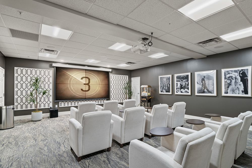 A modern home theater room with plush white seating and a projector screen.