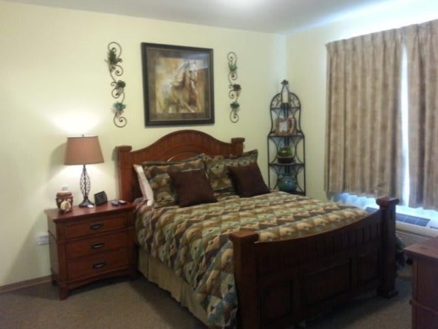 Cozy bedroom with a wooden bed and matching furniture, featuring decorative elements and warm lighting.
