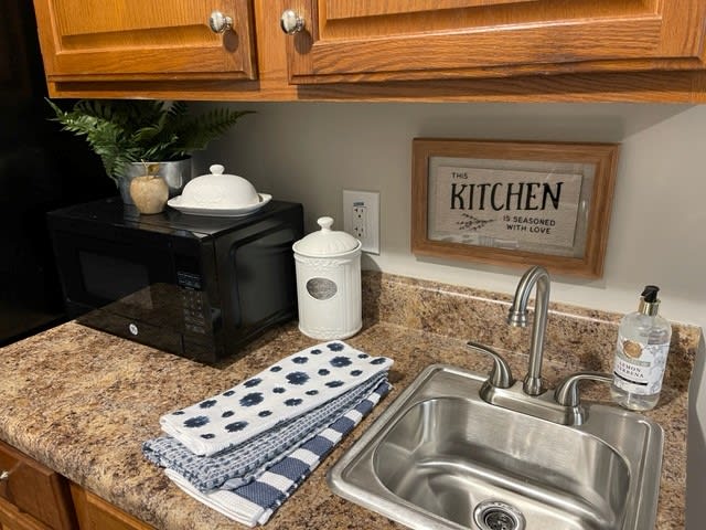 A cozy kitchen counter setup with a sink, microwave, and decorative items.