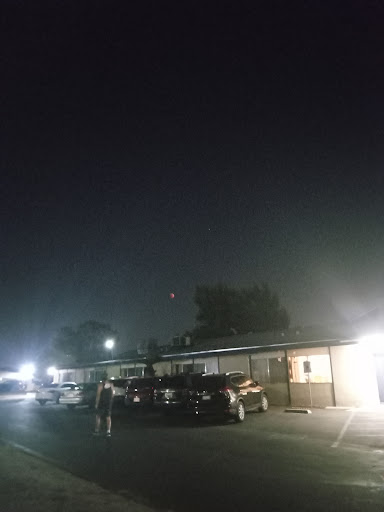 A quiet night at a roadside motel, illuminated by the faint glow of streetlights and surrounded by parked cars.