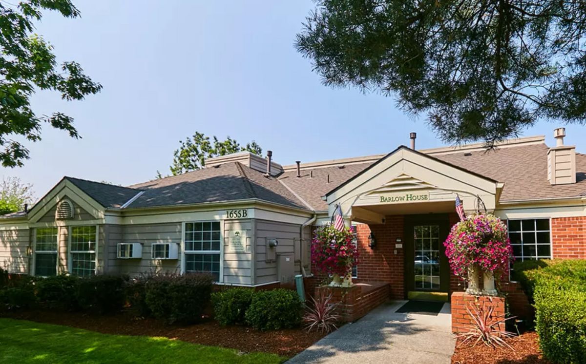 A residential building entrance with well-maintained landscaping under a sunny sky.