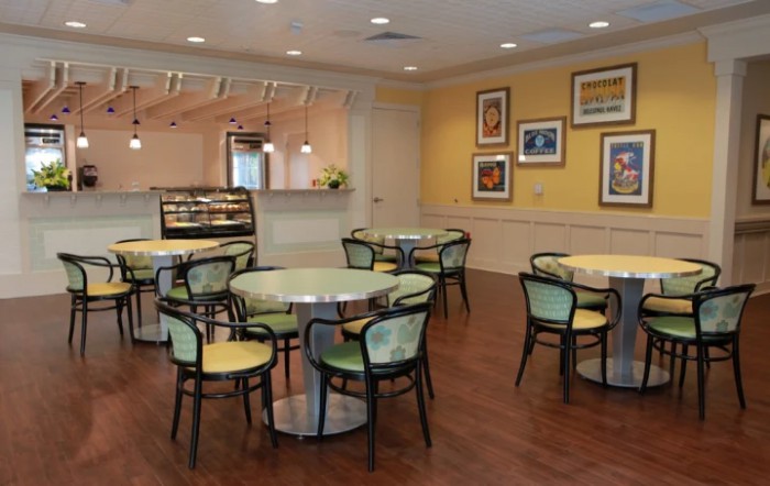 A cozy cafe with round tables and chairs, featuring artwork on the walls.