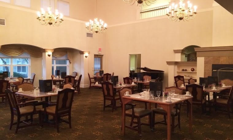 An elegant restaurant dining room with neatly set tables and warm lighting.