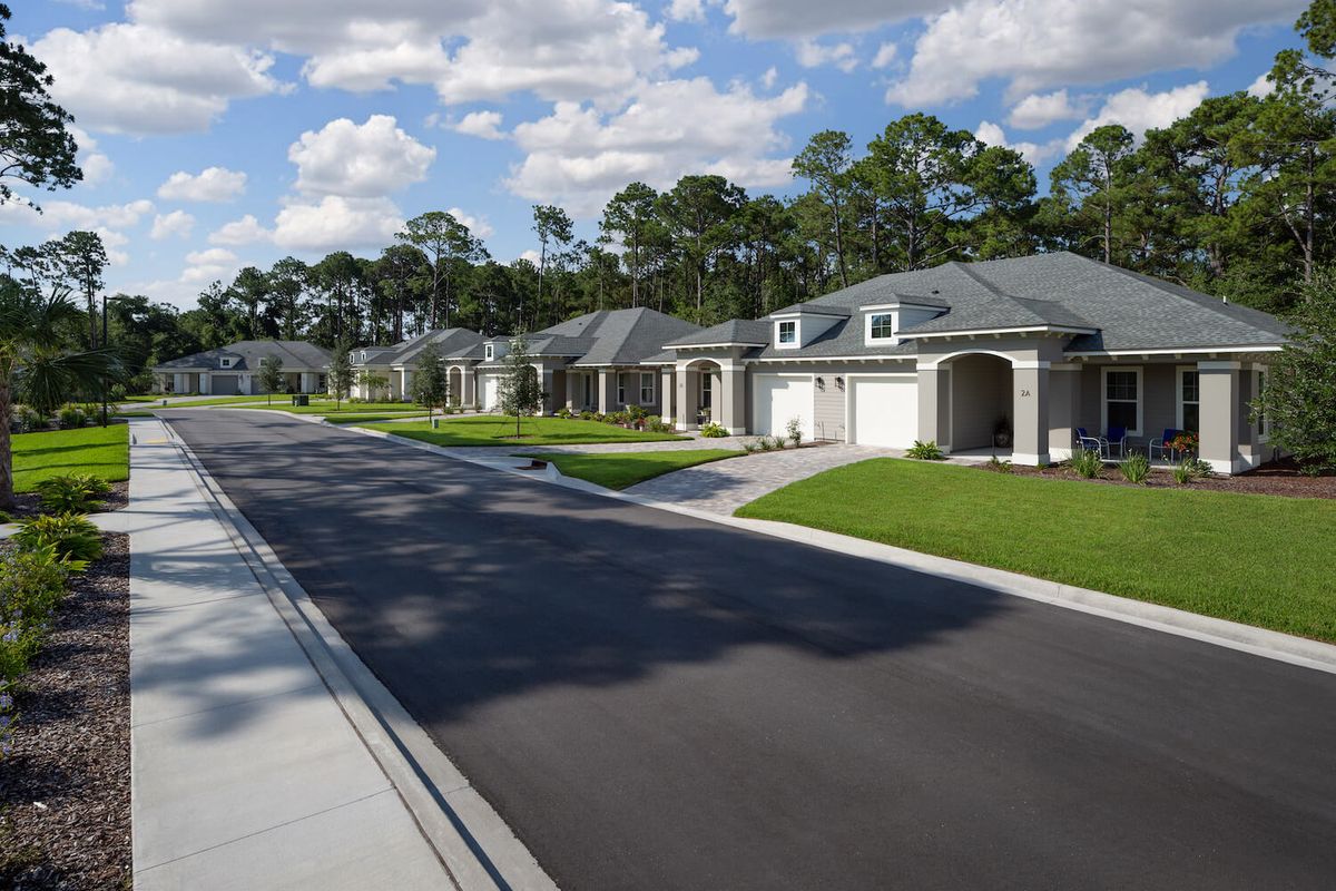 A quiet suburban street lined with modern houses on a sunny day.