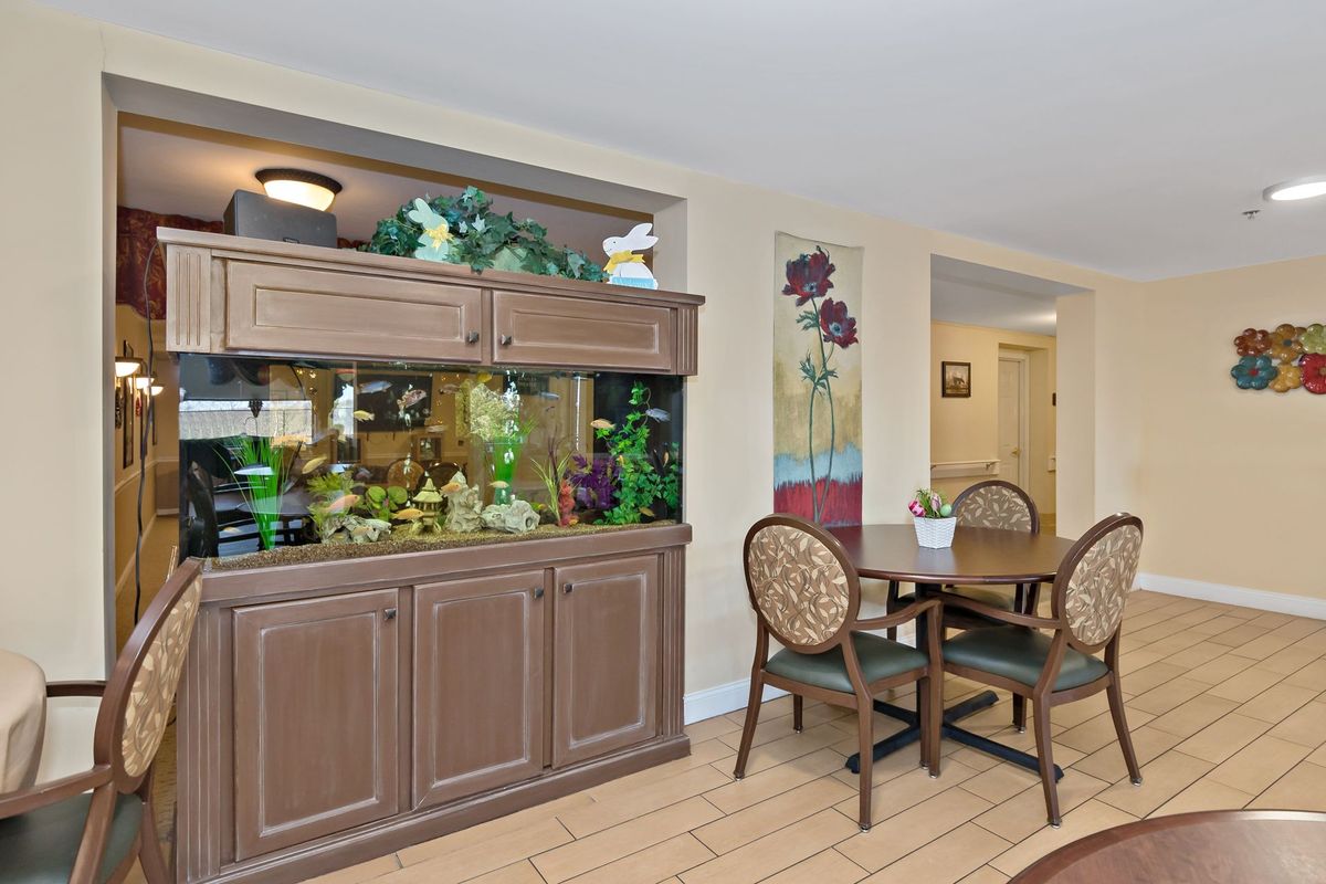 A cozy dining area featuring a wooden table and chairs, complemented by a large fish tank integrated into the cabinetry.
