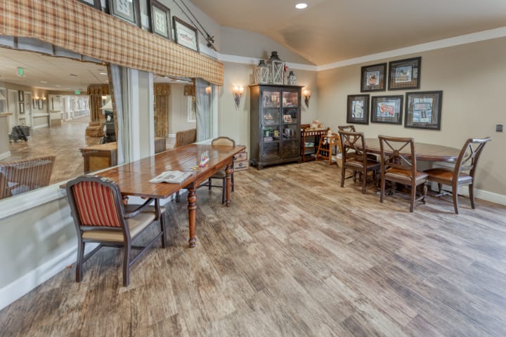 A well-furnished dining room with wooden floors, tables, and chairs.