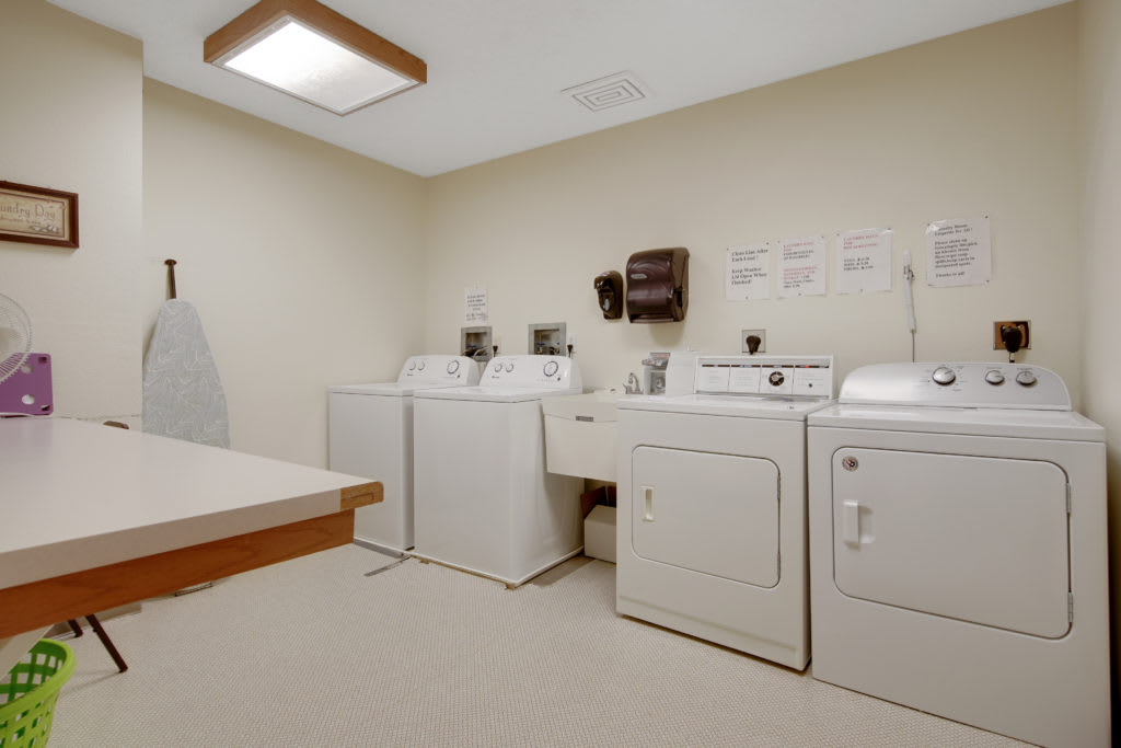 A laundry room with washing machines and dryers.