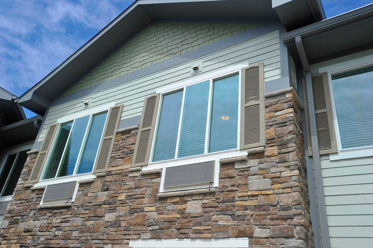 A residential building with a stone facade and multiple windows.