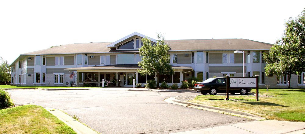 A two-story residential building with a sloped roof and a driveway in front.
