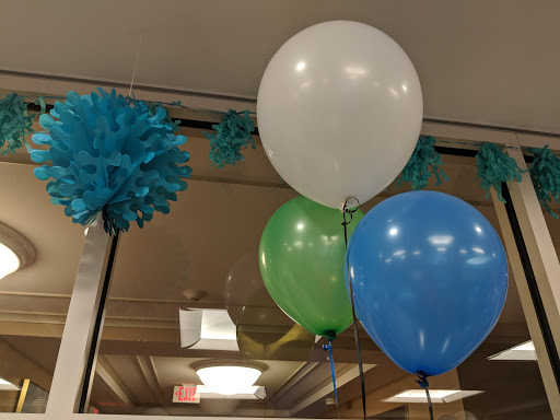 A festive display of colorful balloons and paper pom-poms, perfect for a celebration.