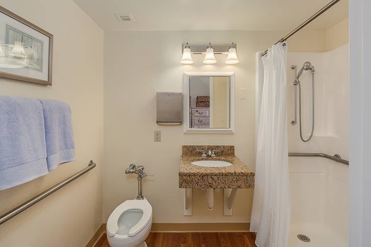 A clean and modern bathroom with a toilet, sink, mirror, and shower area.