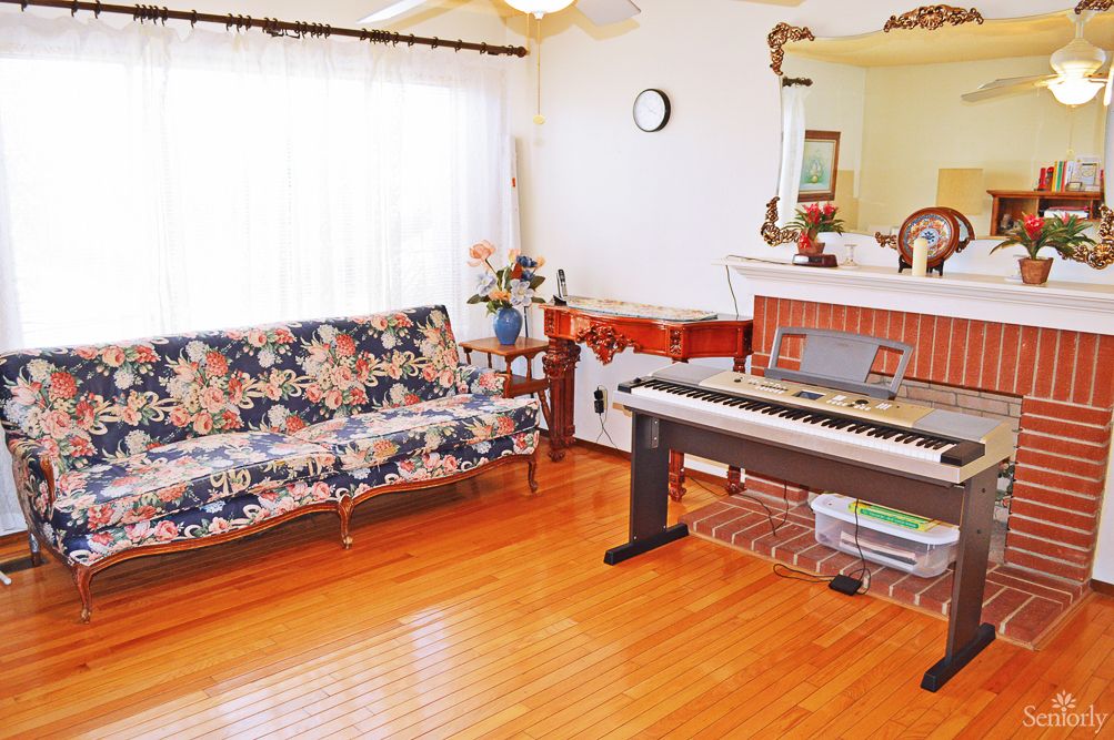 A cozy living room with a piano and floral-patterned couch.