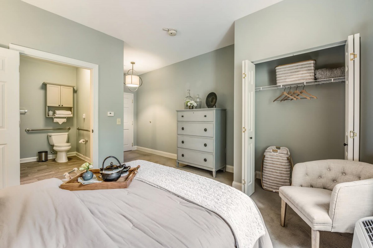 A cozy bedroom with soft pastel colors, featuring a bed, dresser, and open closet.