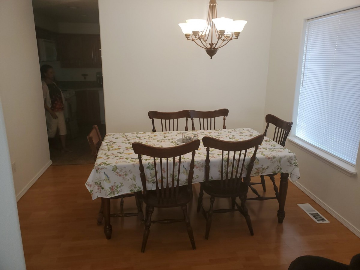 A dining room with a wooden table and chairs under a chandelier.