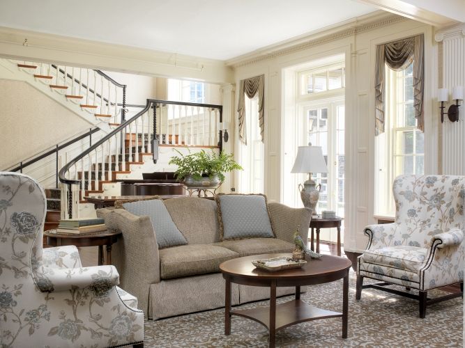 A cozy and elegant living room with a comfortable sofa, armchair, coffee table, and large windows providing natural light.