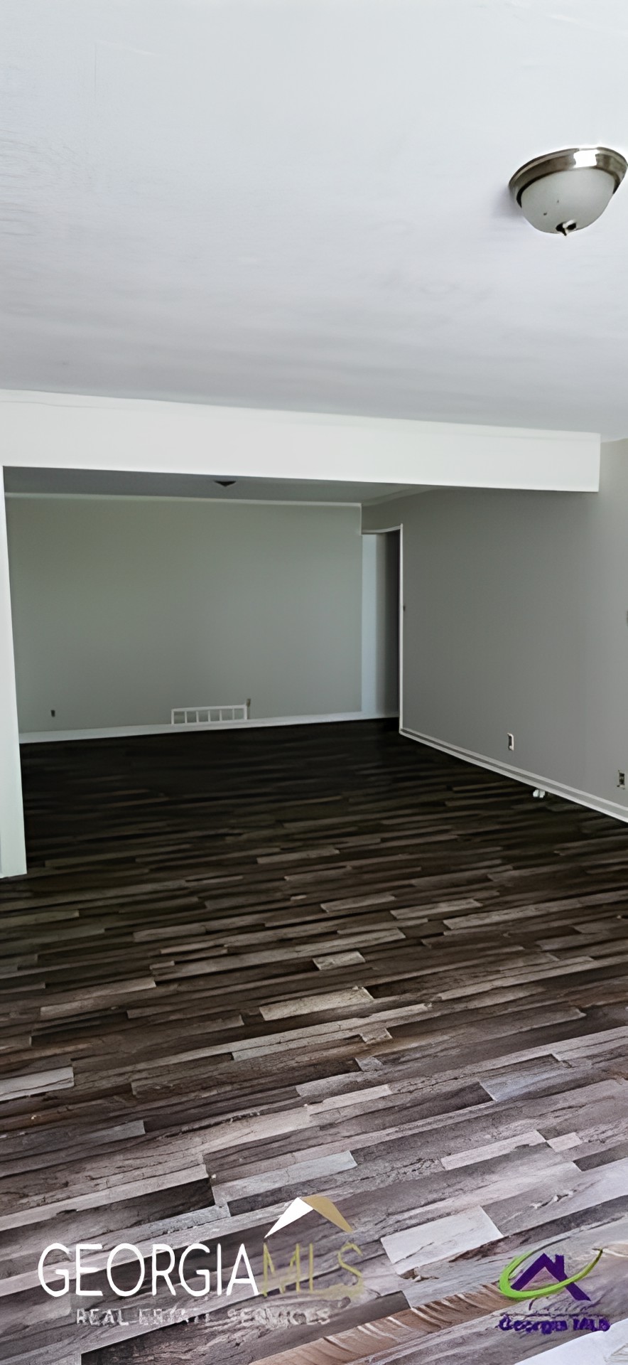 A minimalist, spacious room with a hardwood floor and white walls.