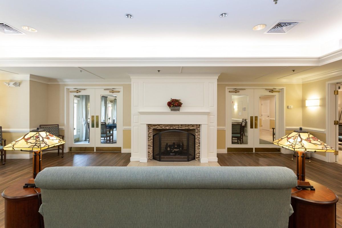 A cozy living room featuring a central fireplace, mirrors on either side, a chandelier, and comfortable seating.