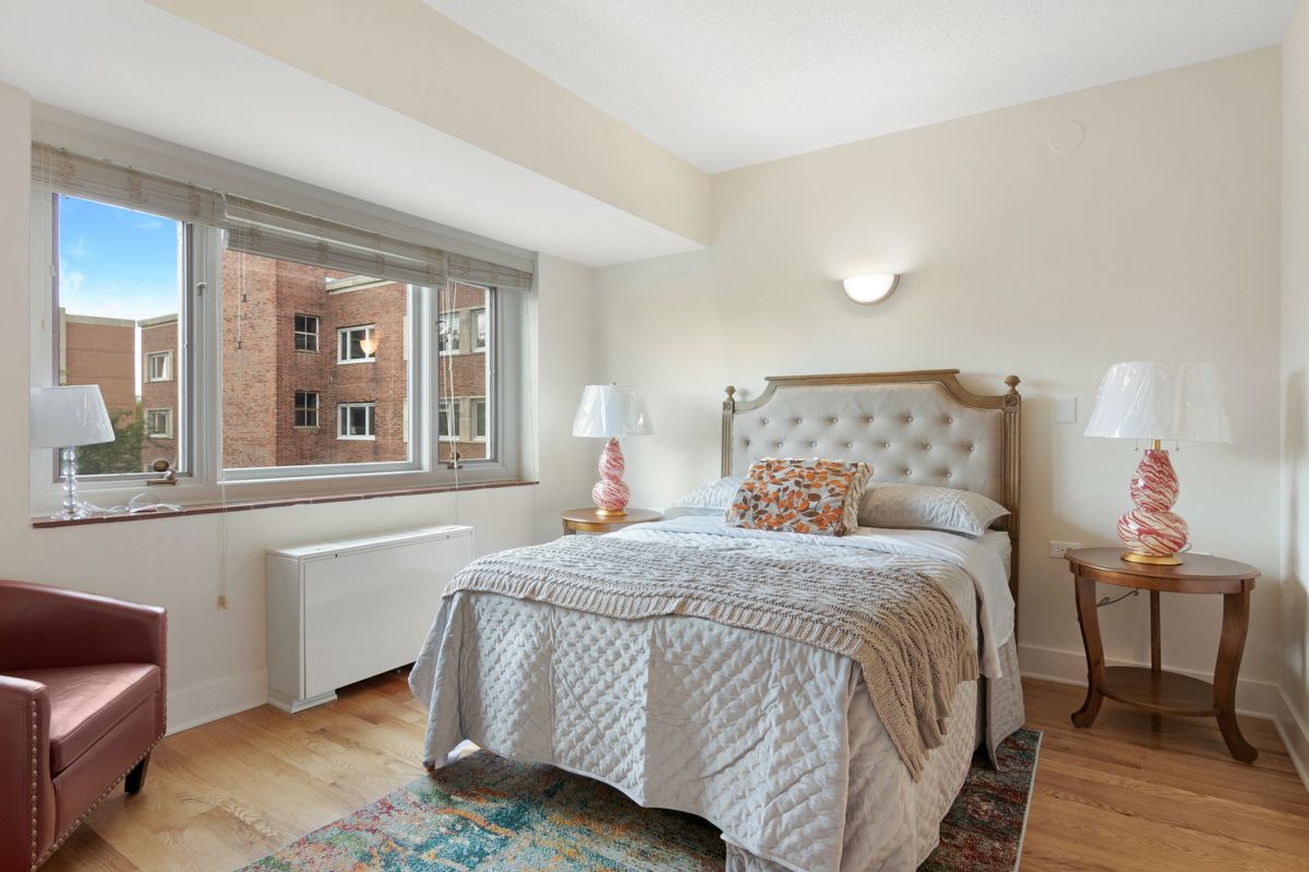 A bright and cozy bedroom with a neatly made bed, large window, and stylish decor.