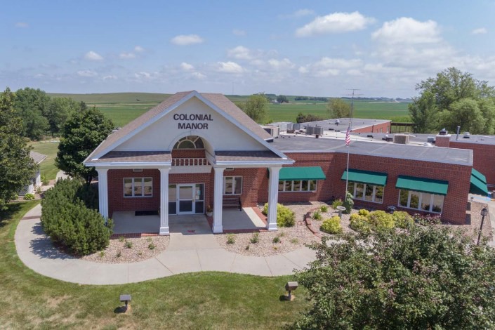 Aerial view of a red brick building with columns, identified as a library, surrounded by landscaping.