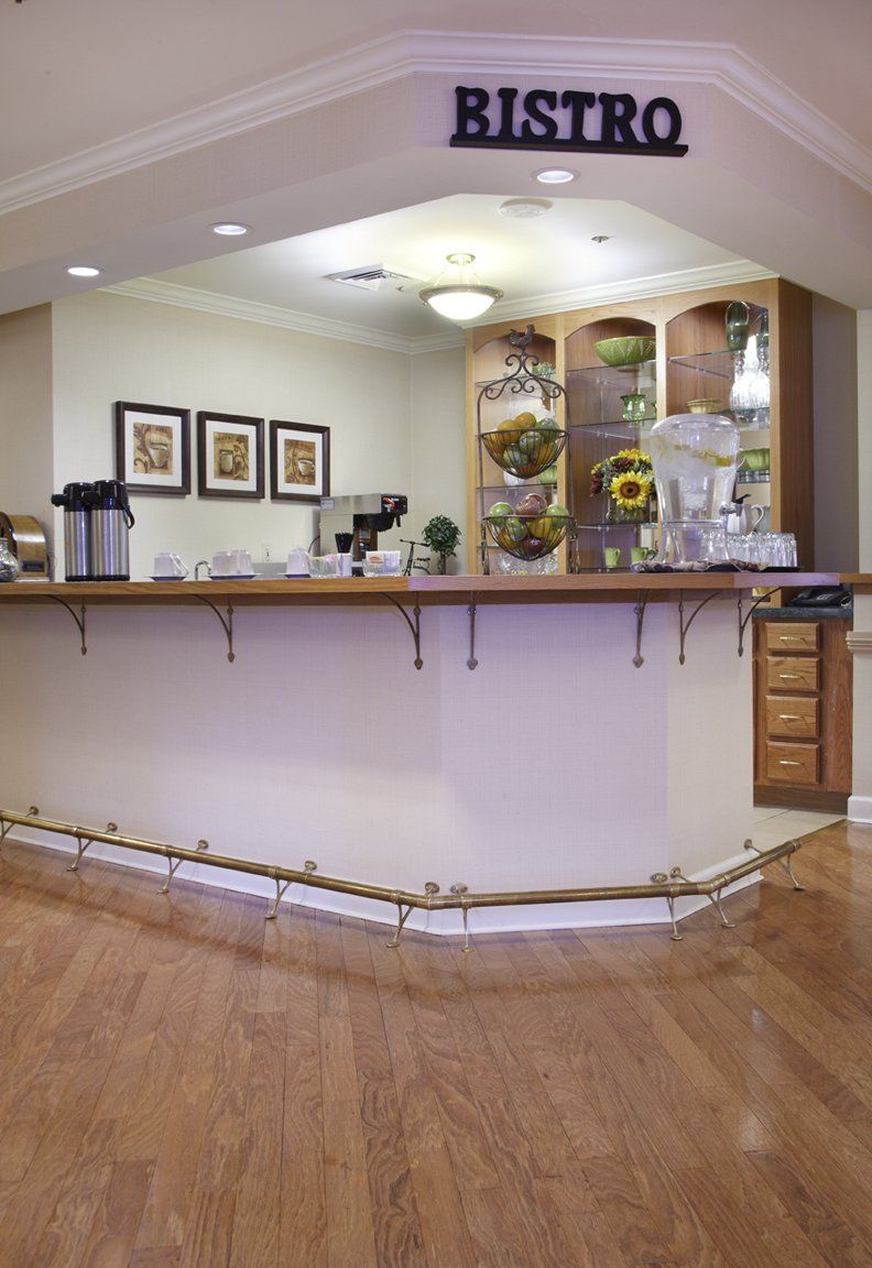 A modern coffee bar features a sleek counter and stylish shelving, complemented by wood flooring and decorative elements.
