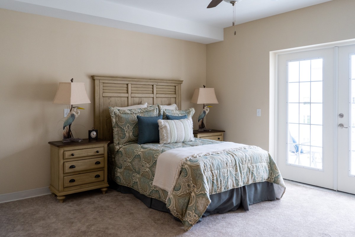 A cozy, well-decorated bedroom featuring a bed with patterned bedding and matching nightstands with lamps.