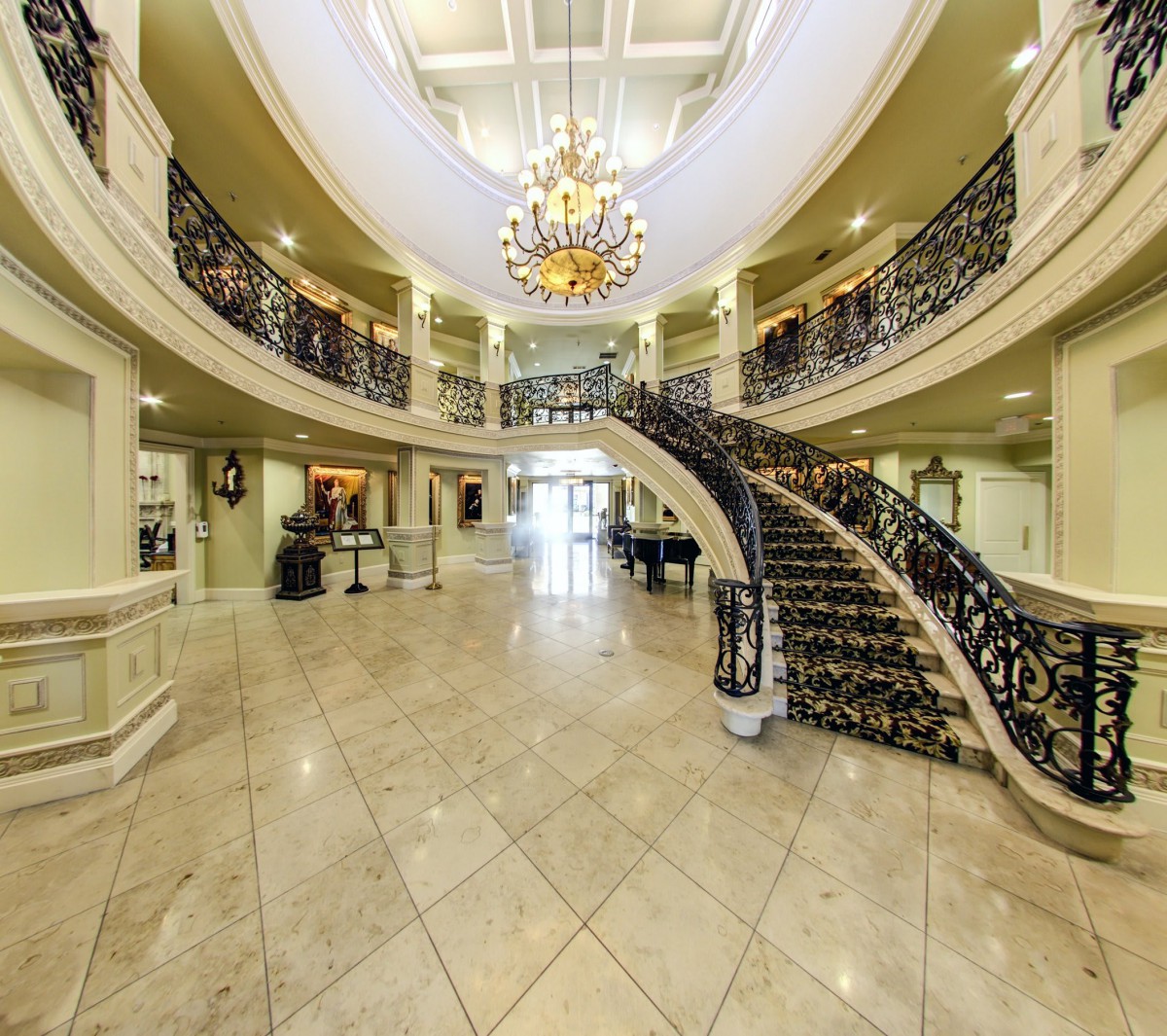 A luxurious lobby featuring a grand curved staircase and an elegant chandelier.