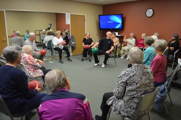 A group of seniors participating in a seated exercise session at a community center.