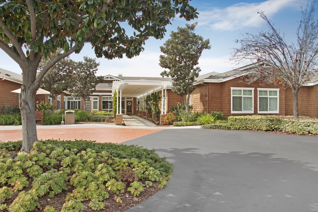 A welcoming entrance to a brick building with well-maintained landscaping and a driveway.