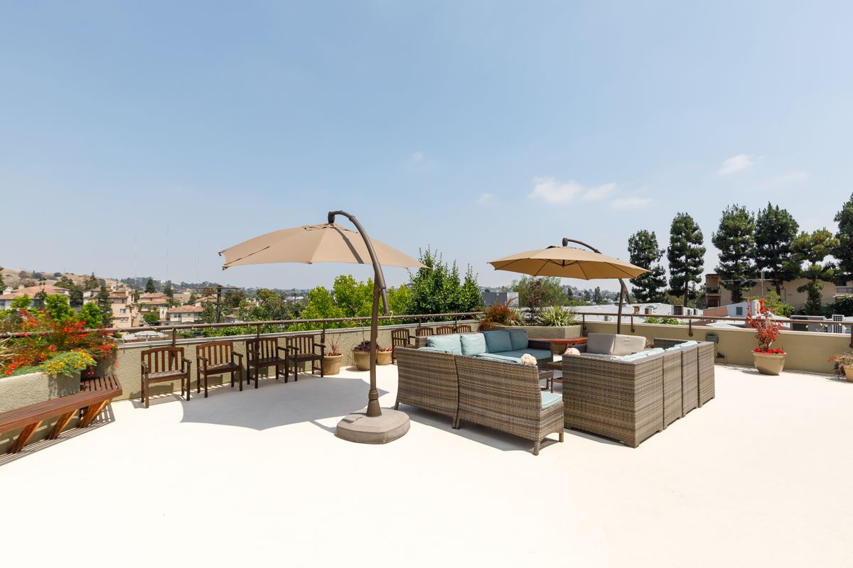 A sunny outdoor patio with comfortable seating and large umbrellas.