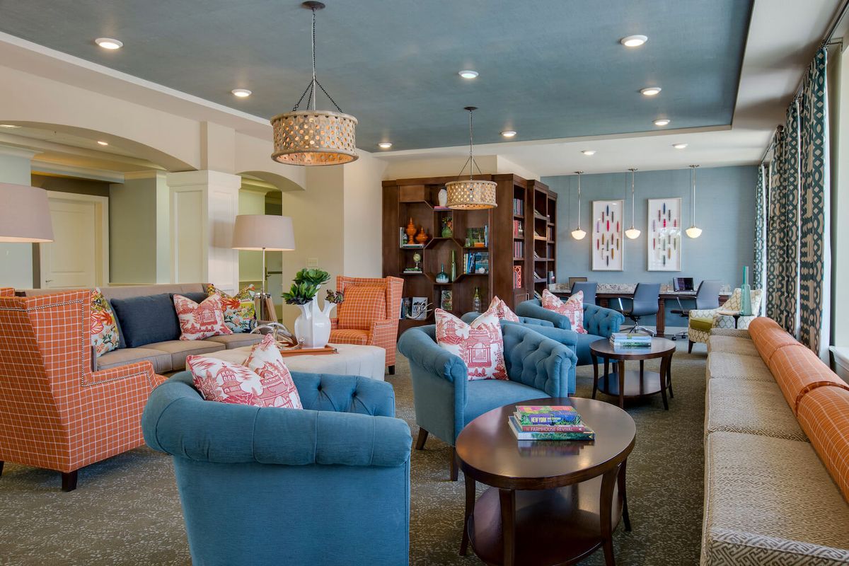 A cozy living room featuring colorful sofas and elegant interior design, complete with bookshelves and a warm ambiance.