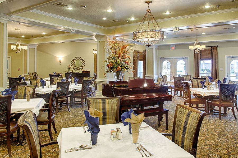 An elegant dining room with a piano and neatly arranged tables and chairs.